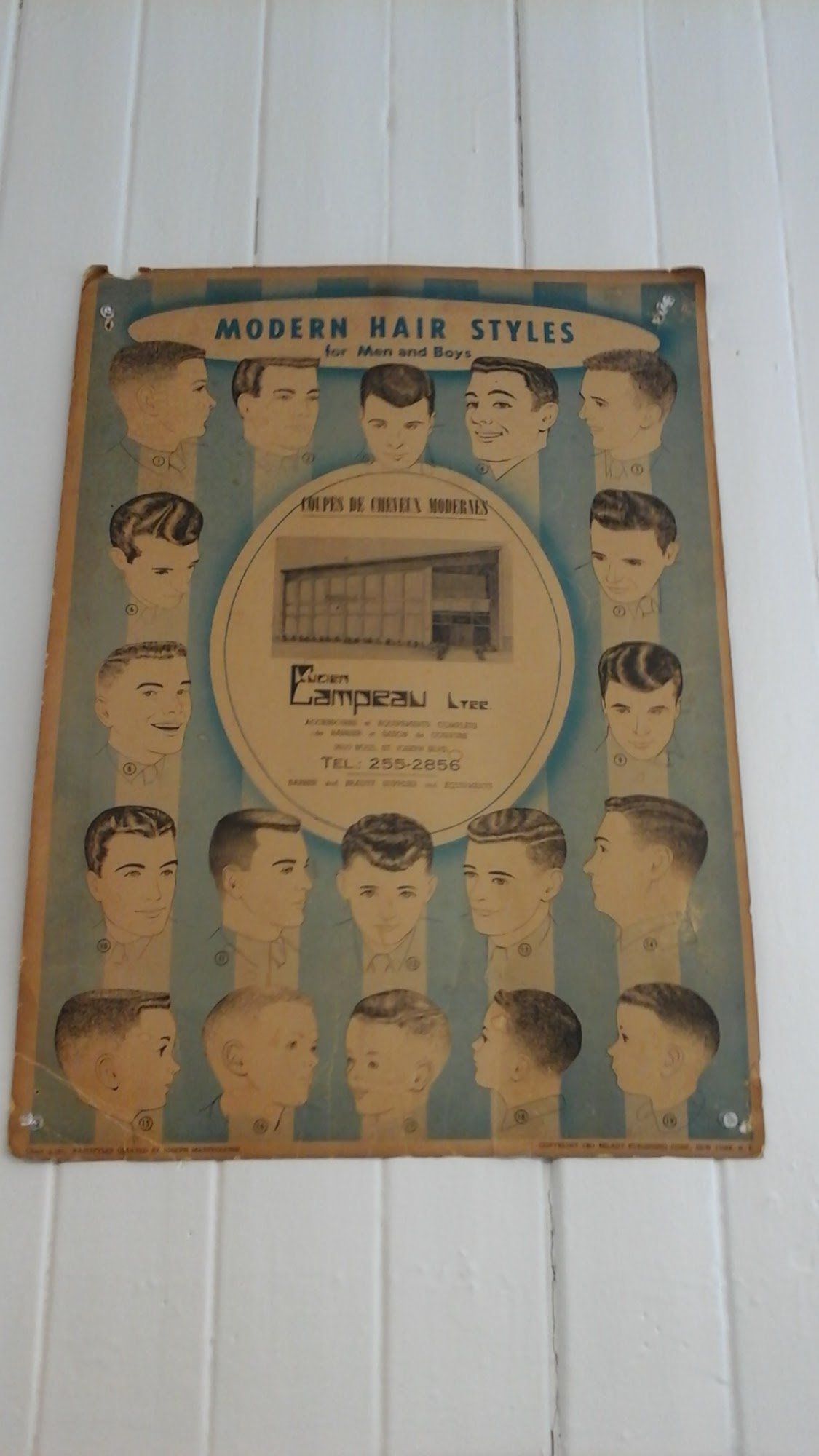 Affiche vintage 'Modern Hair Styles for Men and Boys' accrochée au mur du salon.