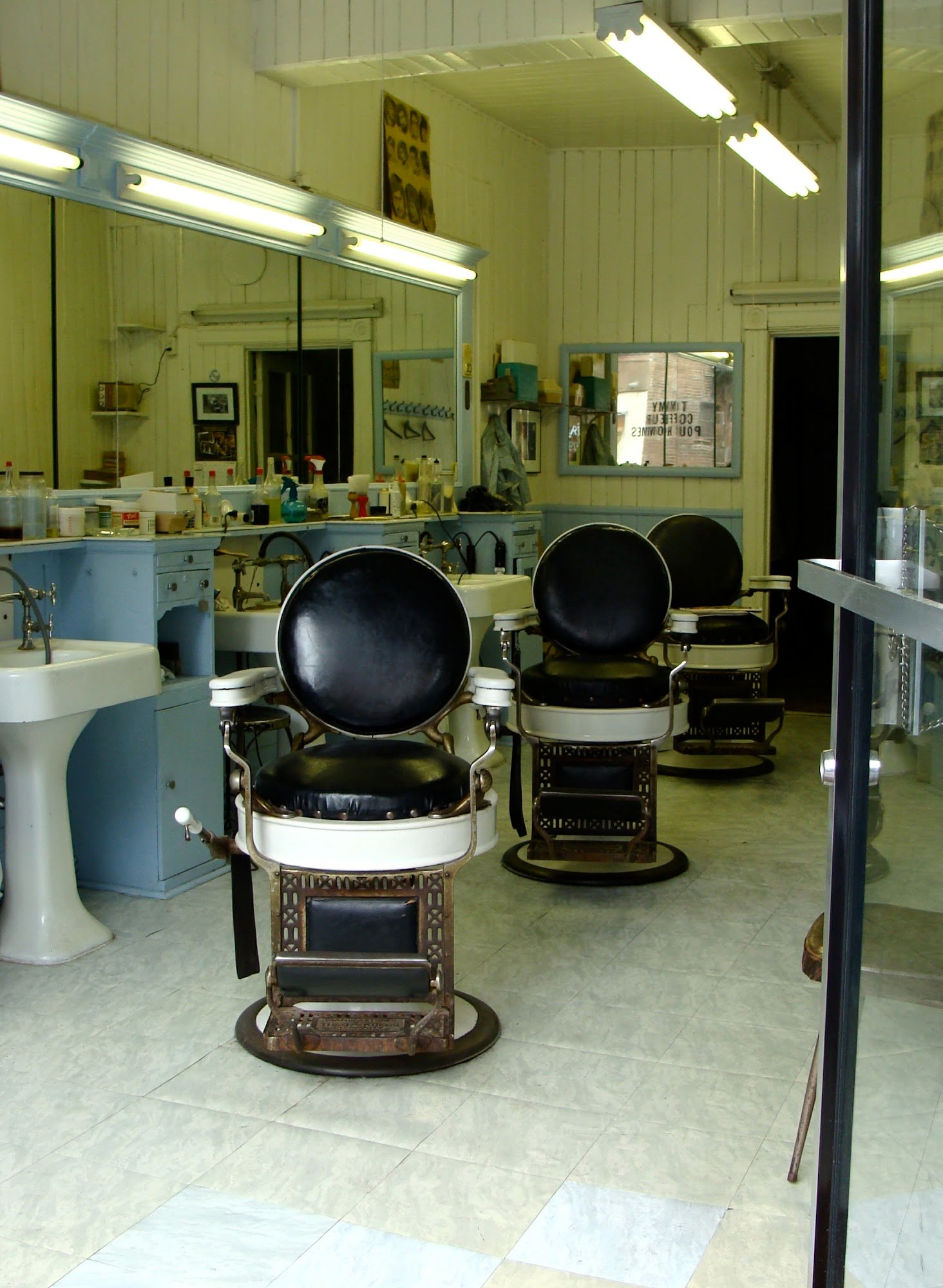 Deux chaises de barbier d'époque devant le mur de miroirs de Coiffure Mile-End.